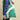 A person in blue jeans carries a white tote bag with green leaf patterns and a visible chocolate bar inside against a plain beige background.
