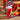 A group of wrapped gifts with brown ribbons sits on a carpet, surrounded by colorful holiday-themed tins shaped like a rocking horse, Christmas tree, and festive scenes.
