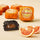 Halved Chocoviar Orange truffle with Sicilian PGI Blood Orange filling, surrounded by orange slices and wrapped chocolates. - AI generated text